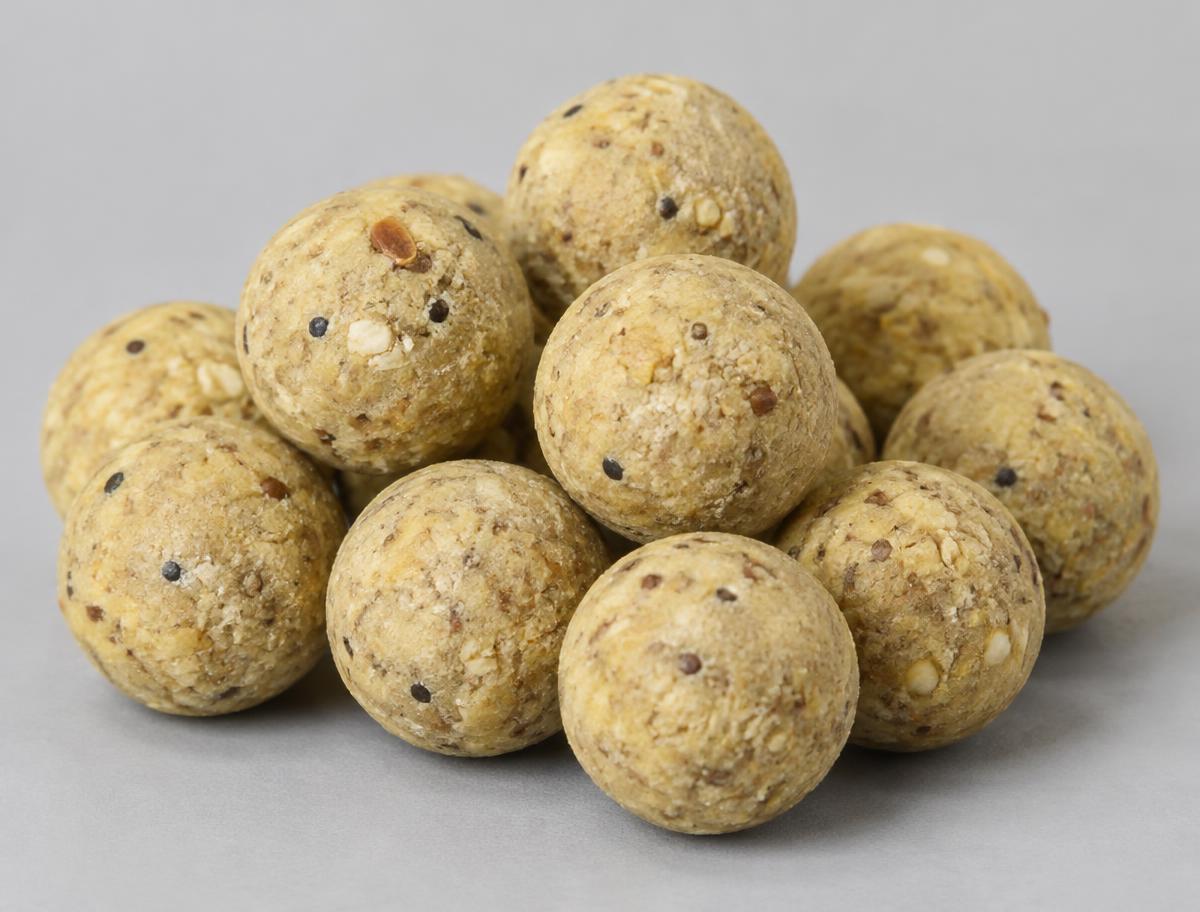 Close-up of pale cream birdfood and nut carp boilies with seed texture